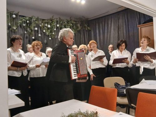 Występ chóru. Dyrygent Antoni Krenc gra na akordeonie